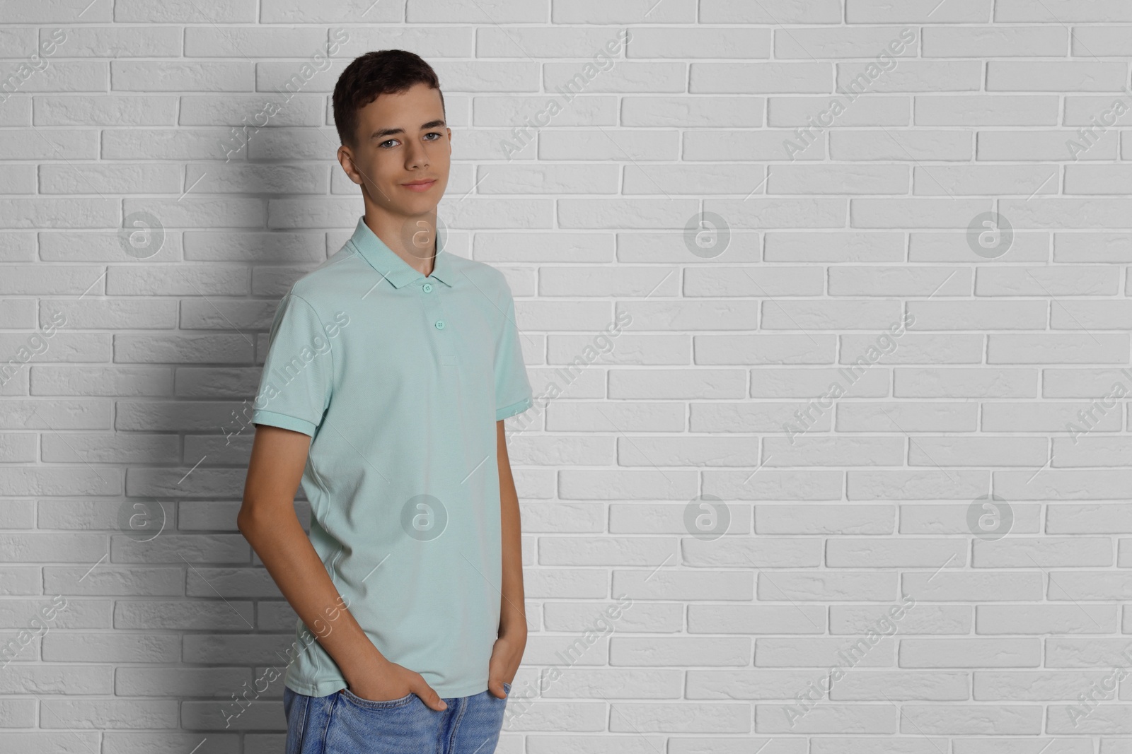 Photo of Teenage boy wearing light green t-shirt near white brick wall, space for text