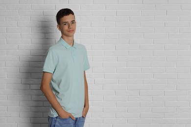 Photo of Teenage boy wearing light green t-shirt near white brick wall, space for text