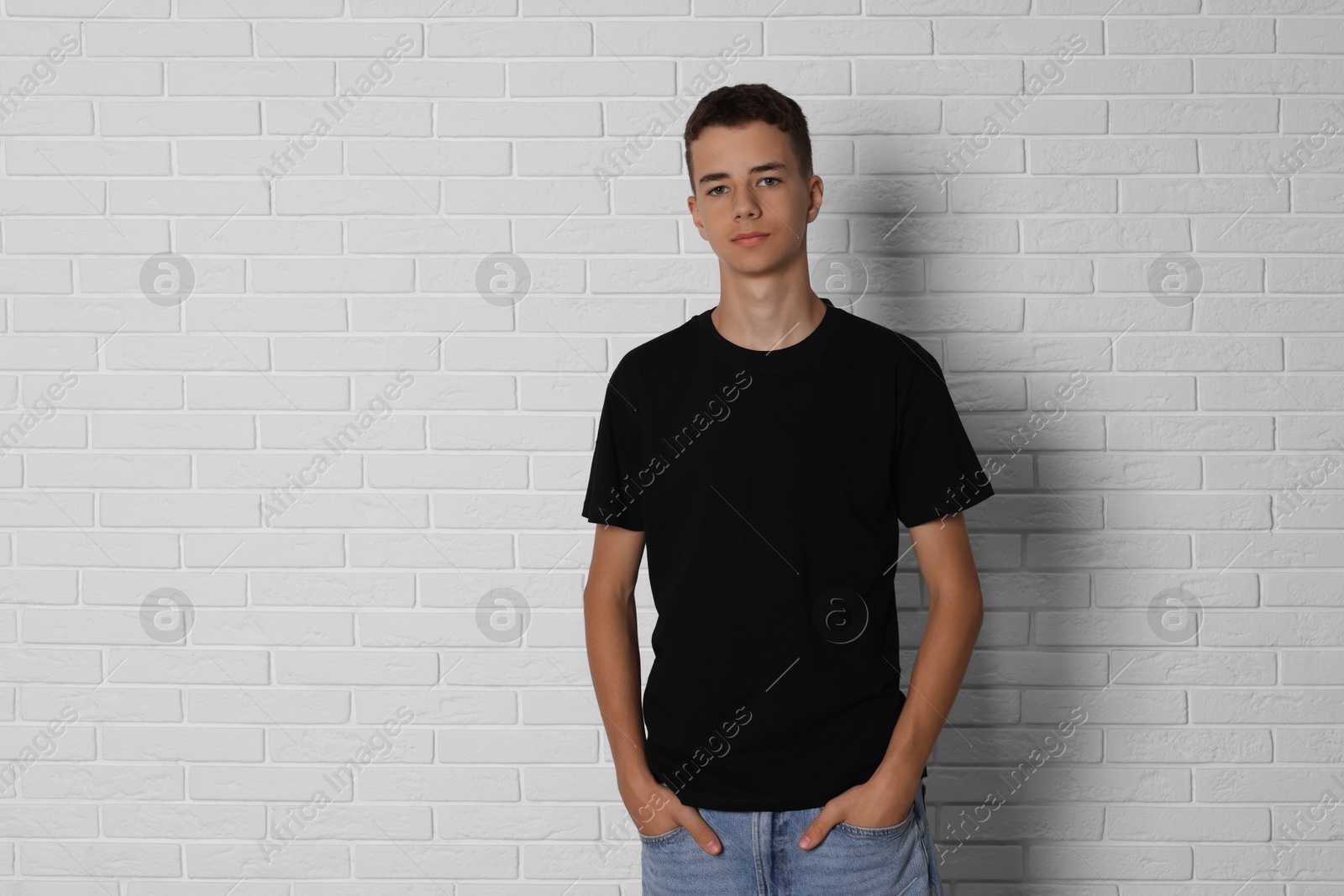 Photo of Teenage boy wearing black t-shirt near white brick wall, space for text