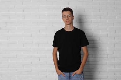 Photo of Teenage boy wearing black t-shirt near white brick wall, space for text