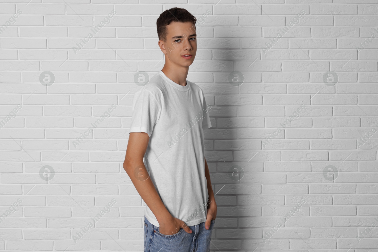 Photo of Teenage boy wearing t-shirt near white brick wall