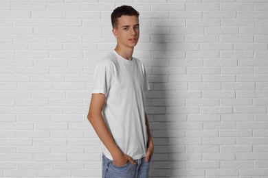 Photo of Teenage boy wearing t-shirt near white brick wall