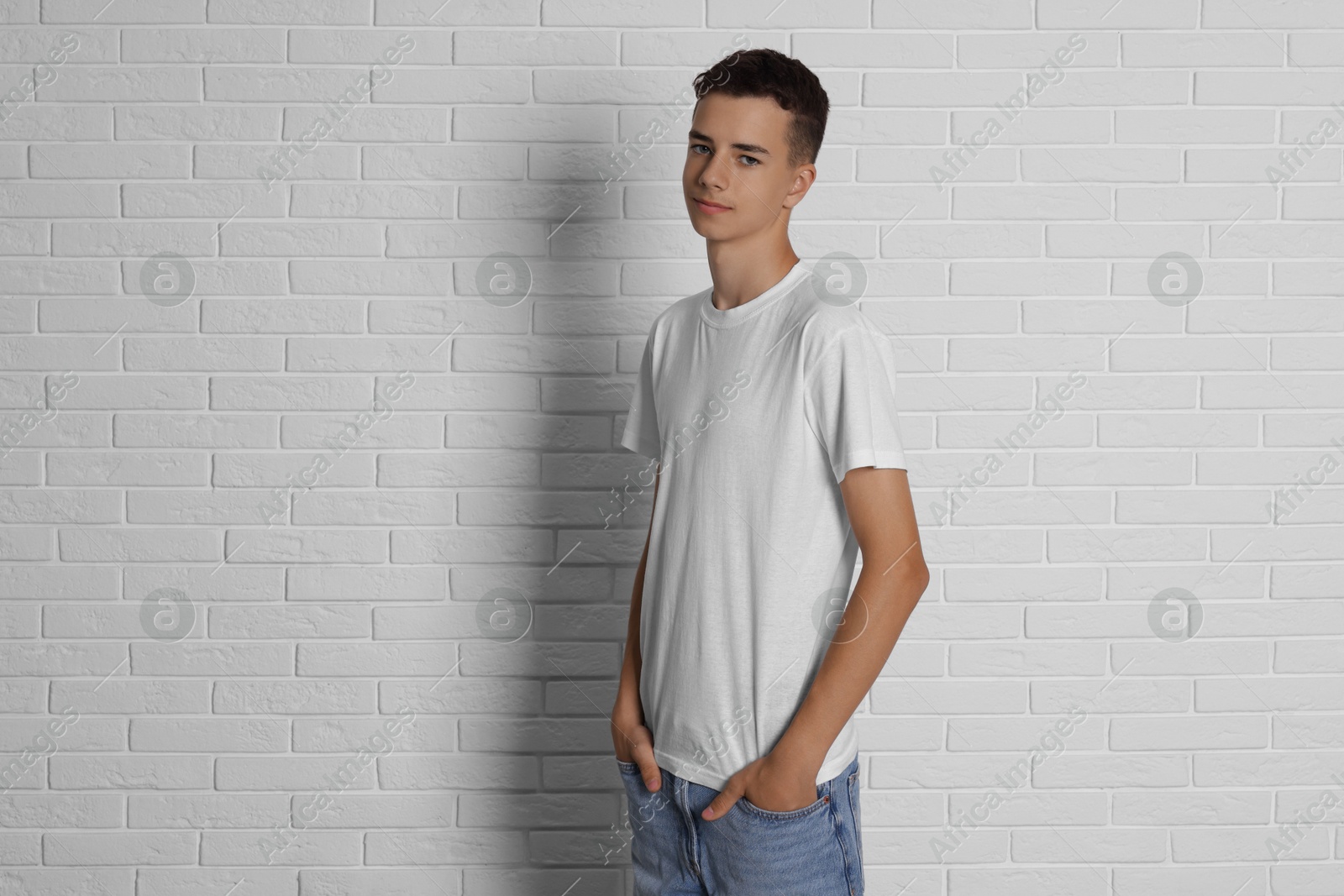 Photo of Teenage boy wearing t-shirt near white brick wall