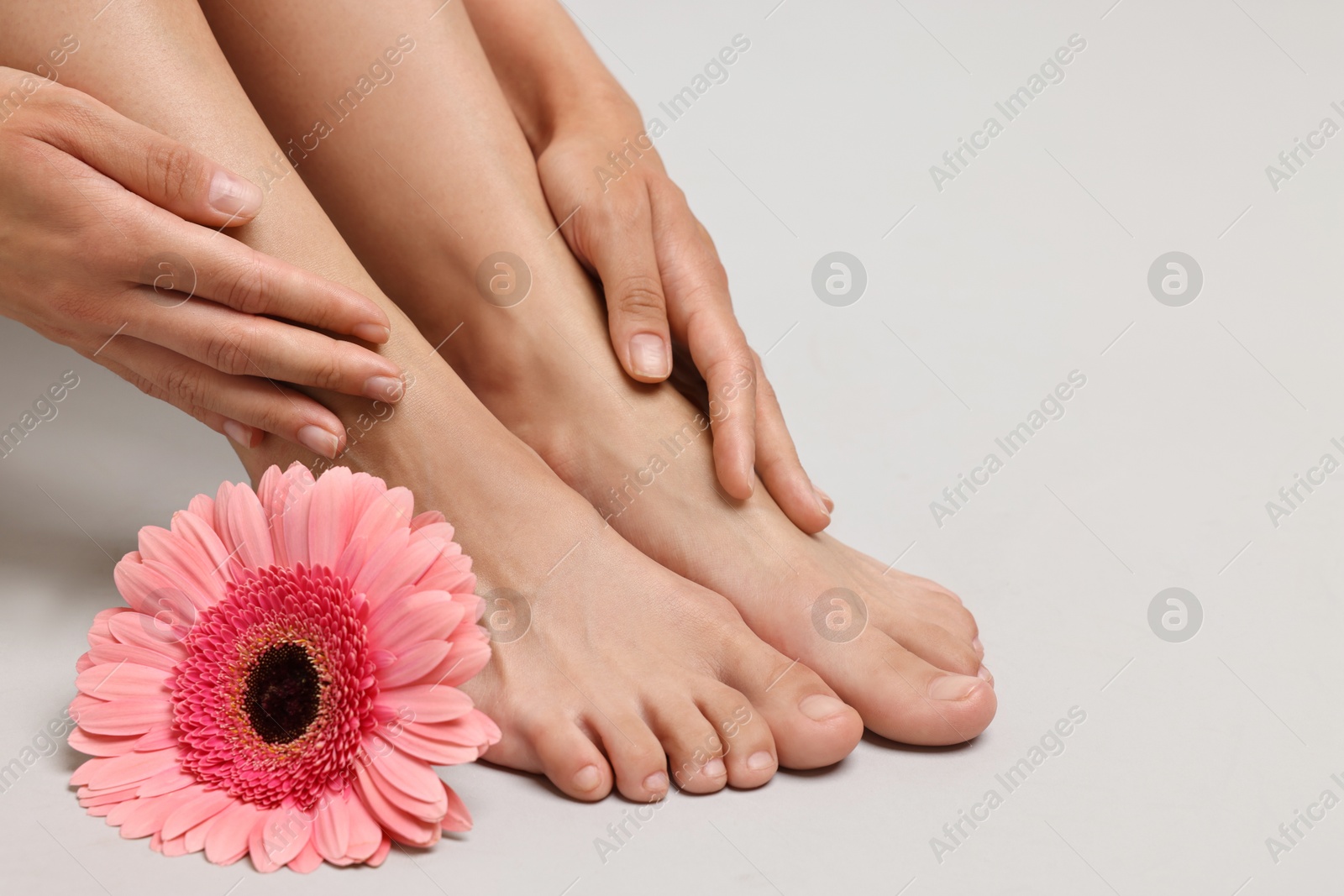 Photo of Woman touching her smooth feet on grey background, closeup