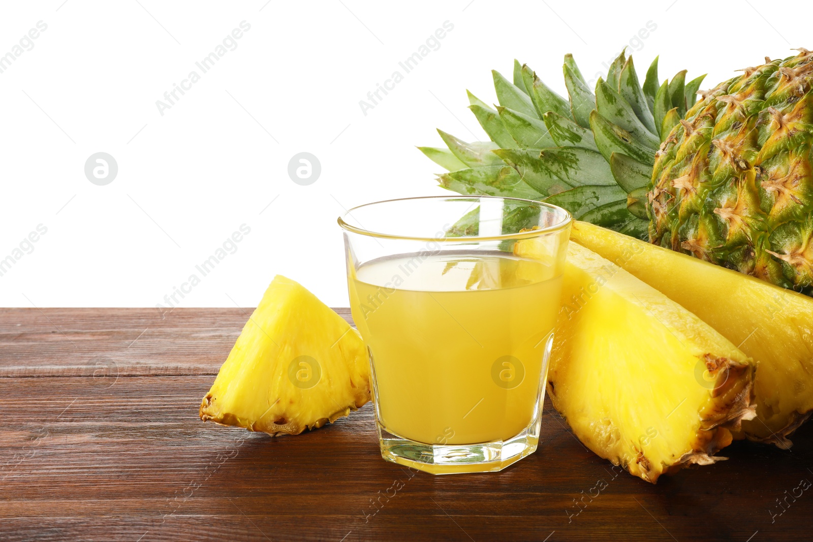 Photo of Glass with pineapple juice and fresh pineapples on wooden table against white background