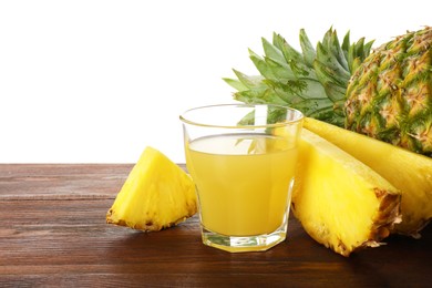 Photo of Glass with pineapple juice and fresh pineapples on wooden table against white background