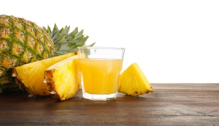 Photo of Glass with pineapple juice and fresh pineapples on wooden table against white background