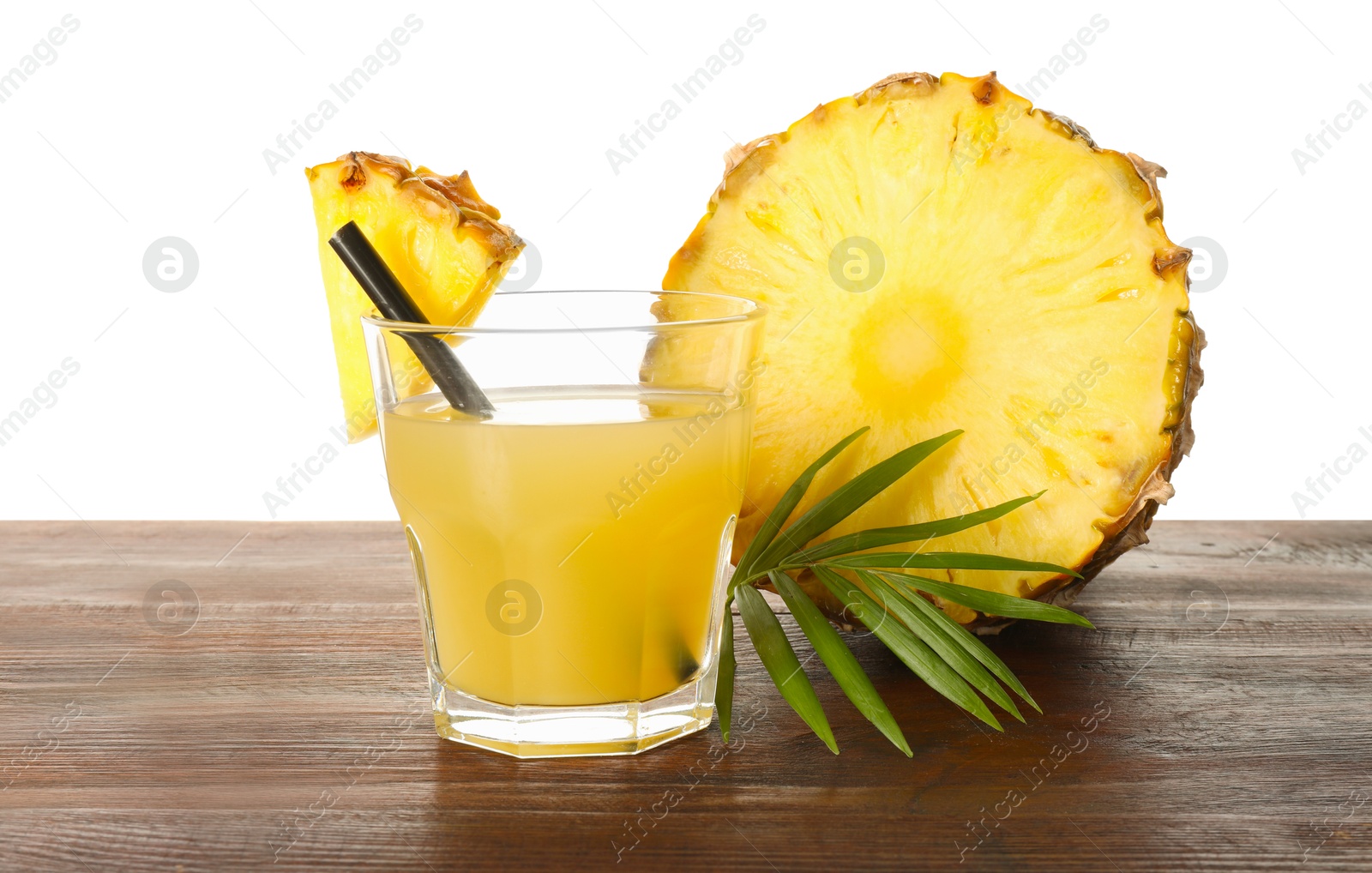 Photo of Glass with pineapple juice and pieces of fresh fruit on wooden table against white background