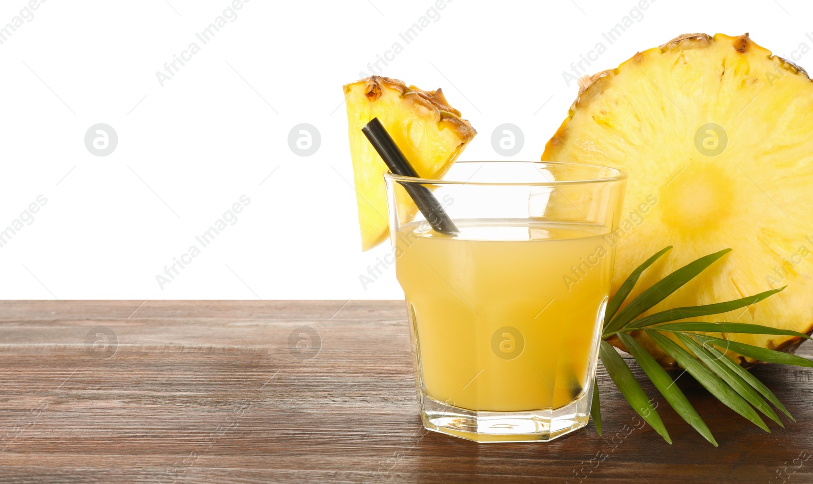 Photo of Glass with pineapple juice and pieces of fresh fruit on wooden table against white background