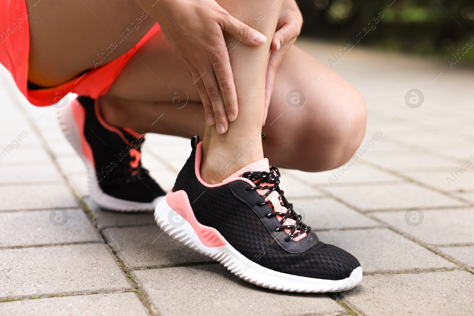 Photo of Woman suffering from foot pain outdoors, closeup