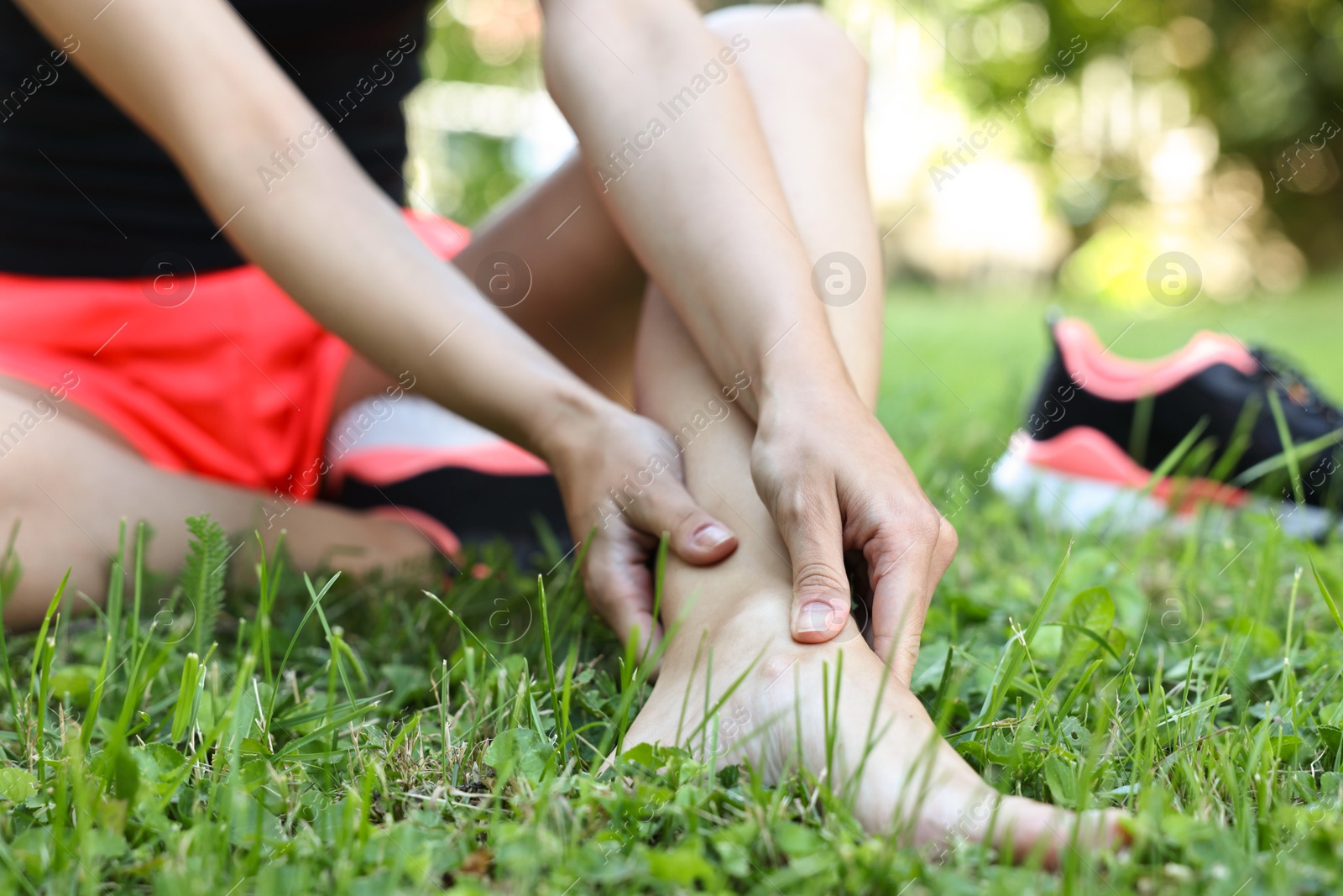 Photo of Woman suffering from foot pain on green grass outdoors, closeup