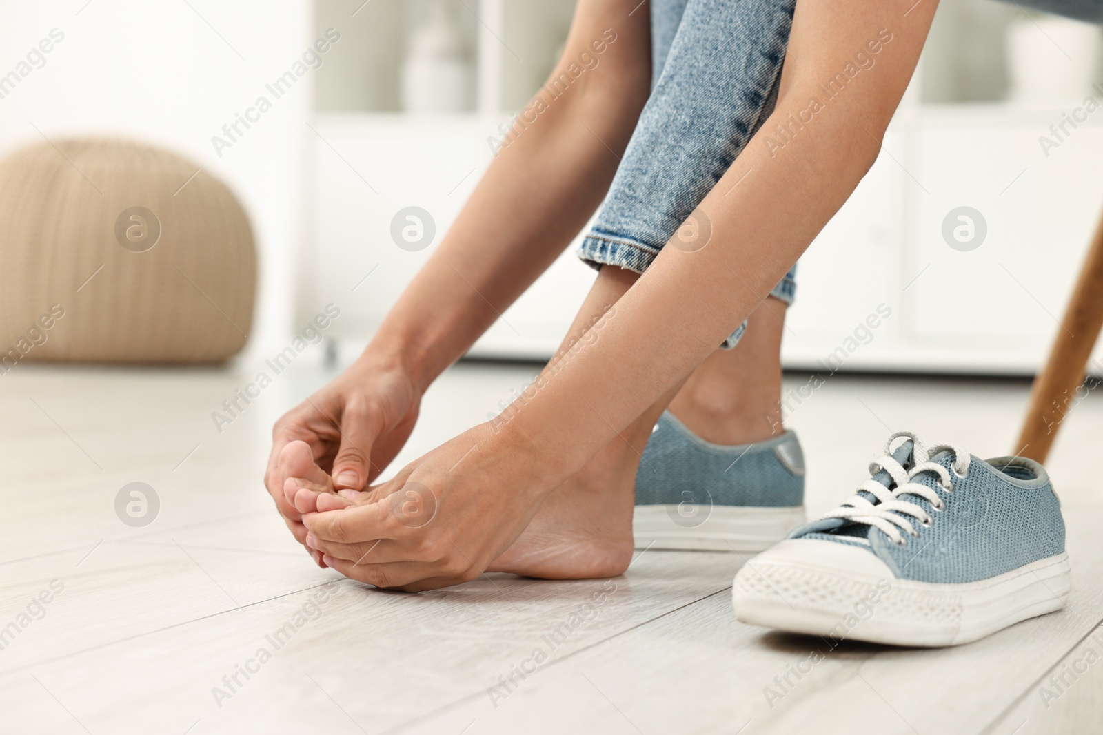 Photo of Woman suffering from foot pain at home, closeup