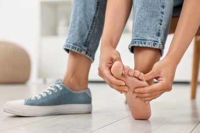 Photo of Woman suffering from foot pain at home, closeup