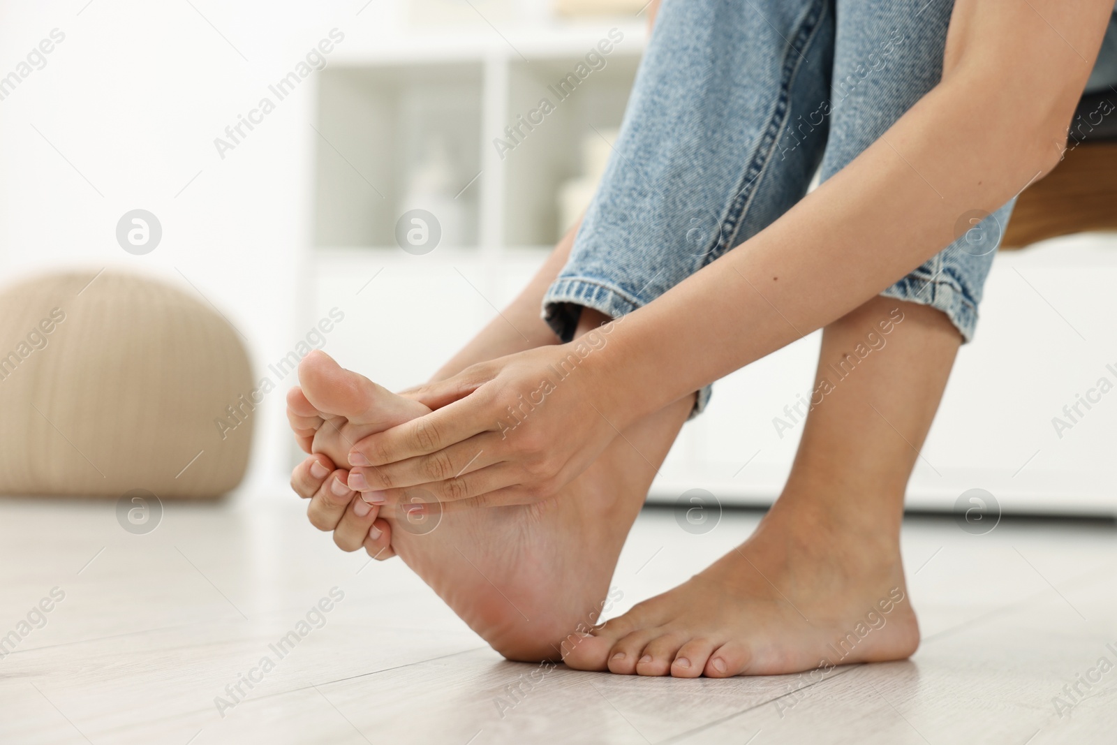 Photo of Woman suffering from foot pain at home, closeup