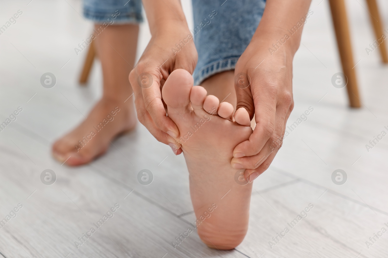 Photo of Woman suffering from foot pain at home, closeup