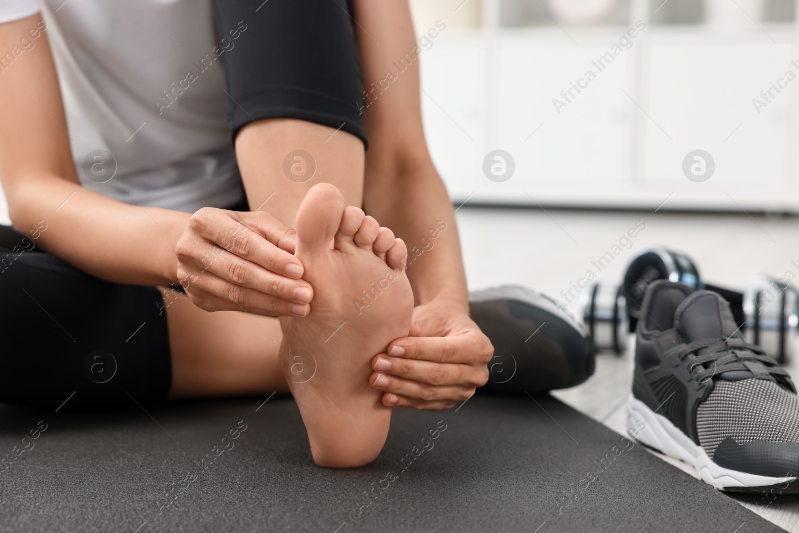 Photo of Woman suffering from foot pain at home, closeup