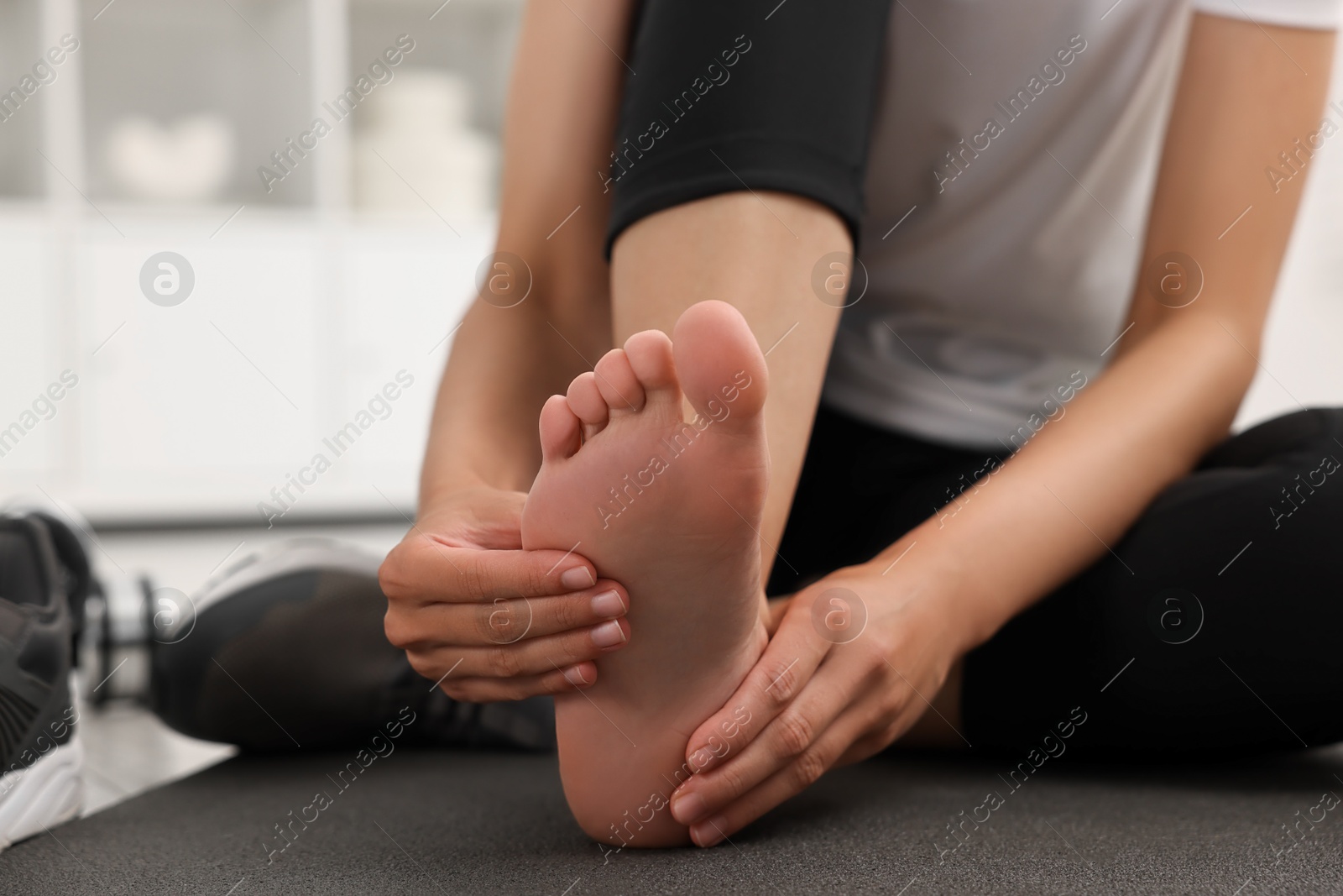 Photo of Woman suffering from foot pain at home, closeup