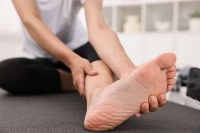 Photo of Woman suffering from foot pain at home, closeup