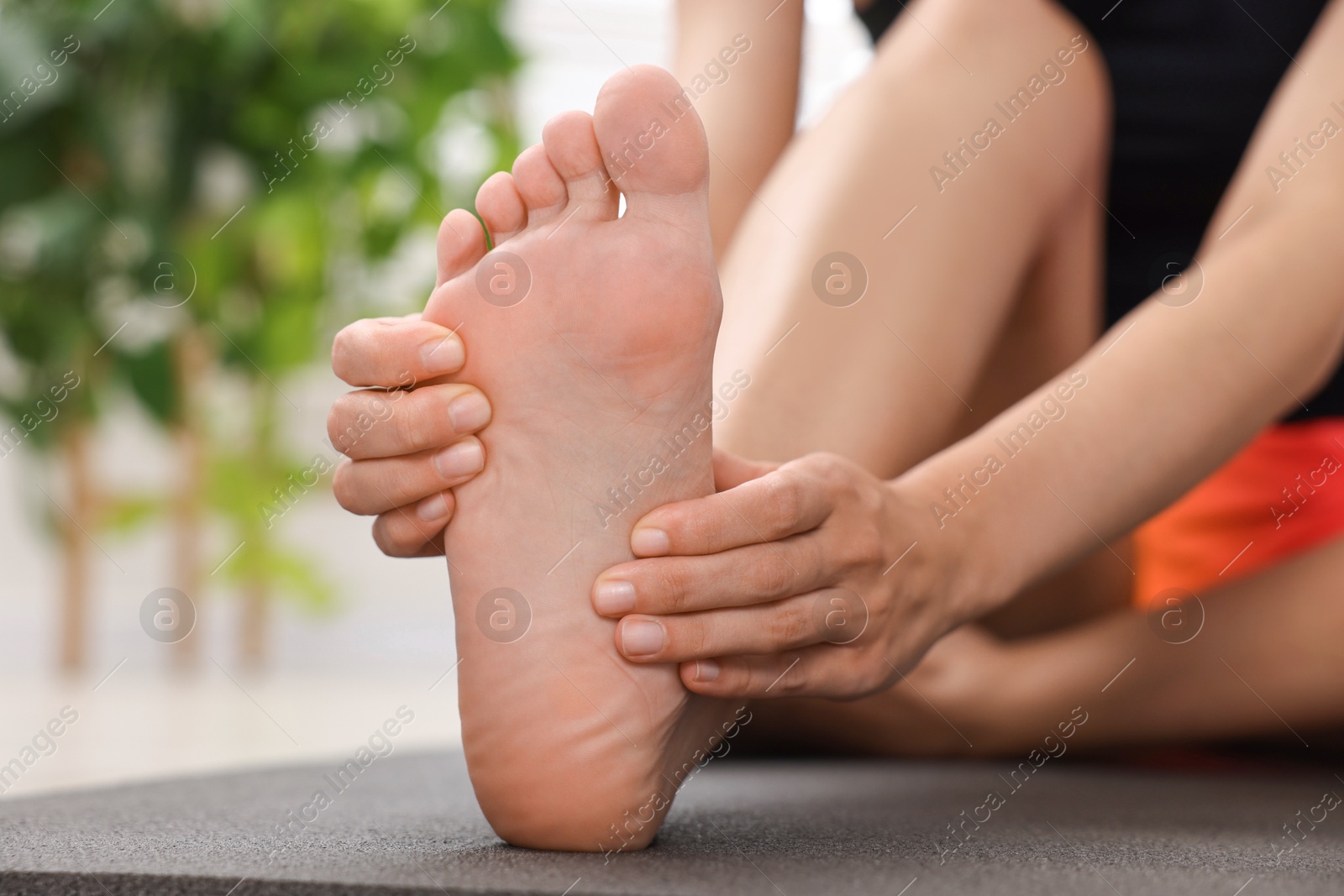 Photo of Woman suffering from foot pain at home, closeup