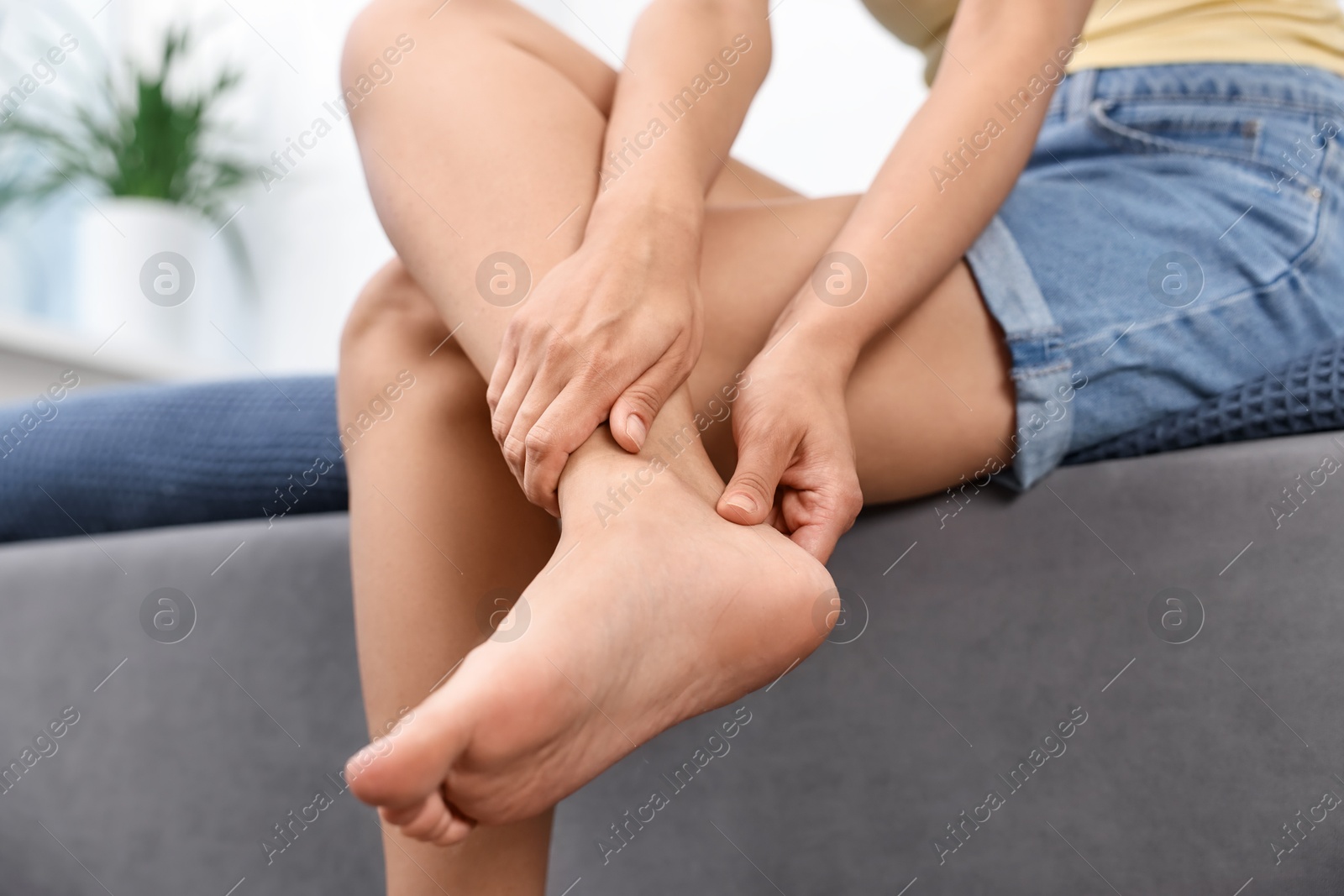 Photo of Woman suffering from foot pain on bed at home, closeup