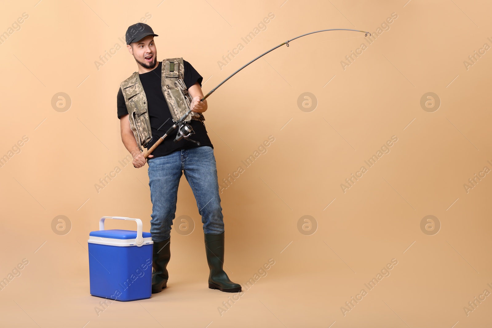 Photo of Emotional fisherman with rod and cooler box fishing on beige background