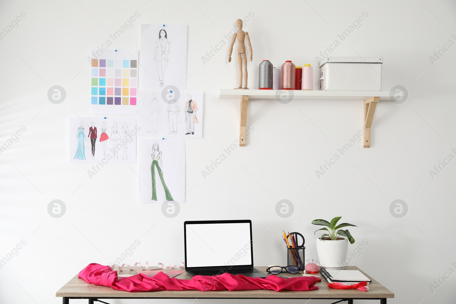 Photo of Fashion designer`s workplace with laptop, sketches of new outfits and other supplies