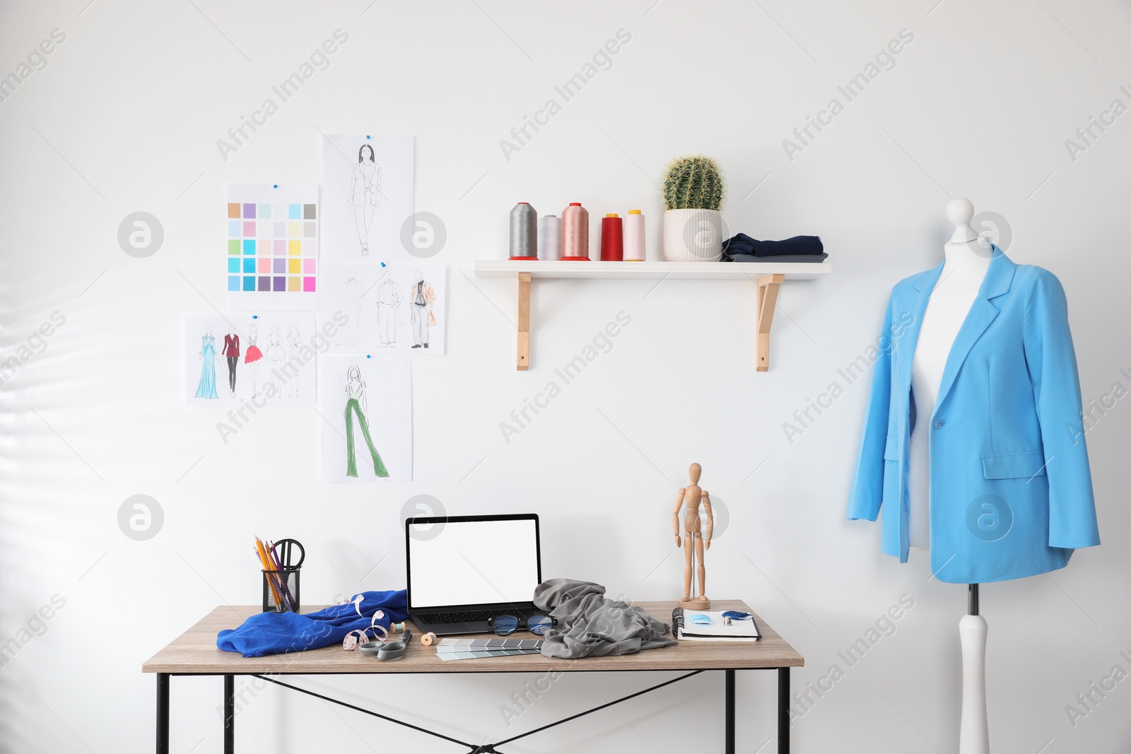 Photo of Fashion designer`s workplace with laptop, sketches of new outfits and other supplies