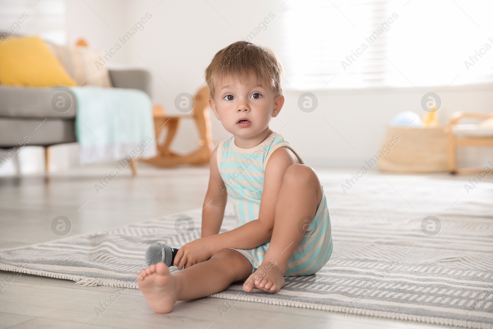 Photo of Cute little baby with microphone on floor at home