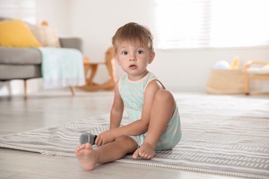 Cute little baby with microphone on floor at home