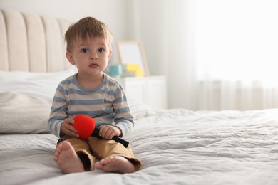 Cute little baby with microphone on bed at home, space for text