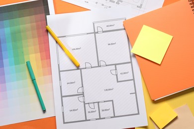 Photo of Designer's workplace with house plan, color palette and stationery on orange table, flat lay