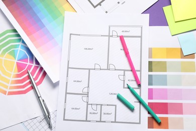 Photo of Designer's workplace with house plans, color palettes and stationery on table, top view