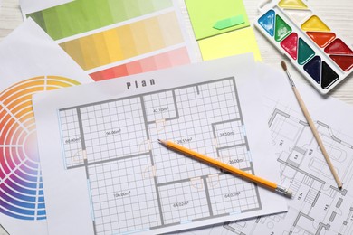 Photo of Designer's workplace with house plans, color palettes and stationery on light wooden table, flat lay