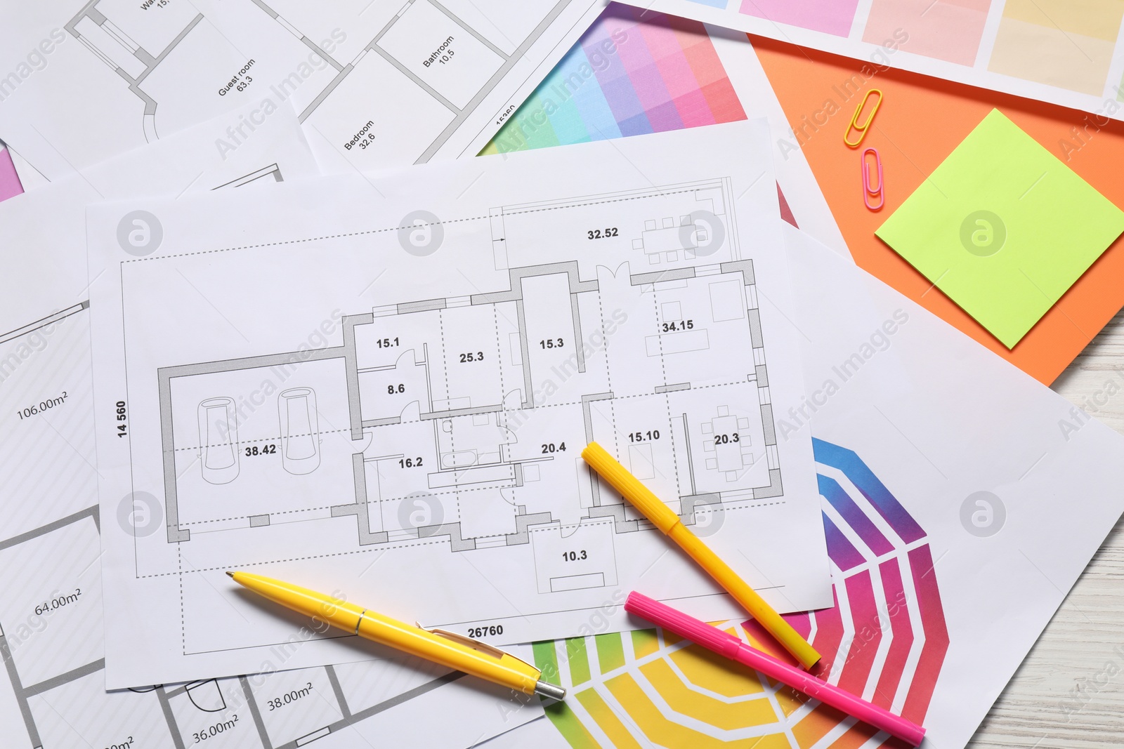 Photo of Designer's workplace with house plans, color palettes and stationery on light wooden table, flat lay