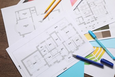 Photo of Designer's workplace with house plans, color palettes and stationery on wooden table, flat lay