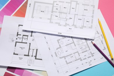 Designer's workplace with house plans, color palettes and pencils on table, top view