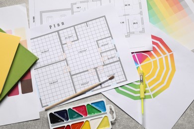 Photo of Designer's workplace with house plans, color palettes and stationery on grey table, flat lay