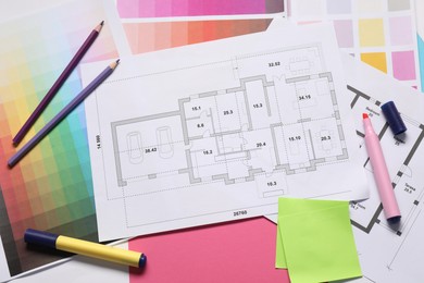 Photo of Designer's workplace with house plans, color palettes and stationery on table, top view