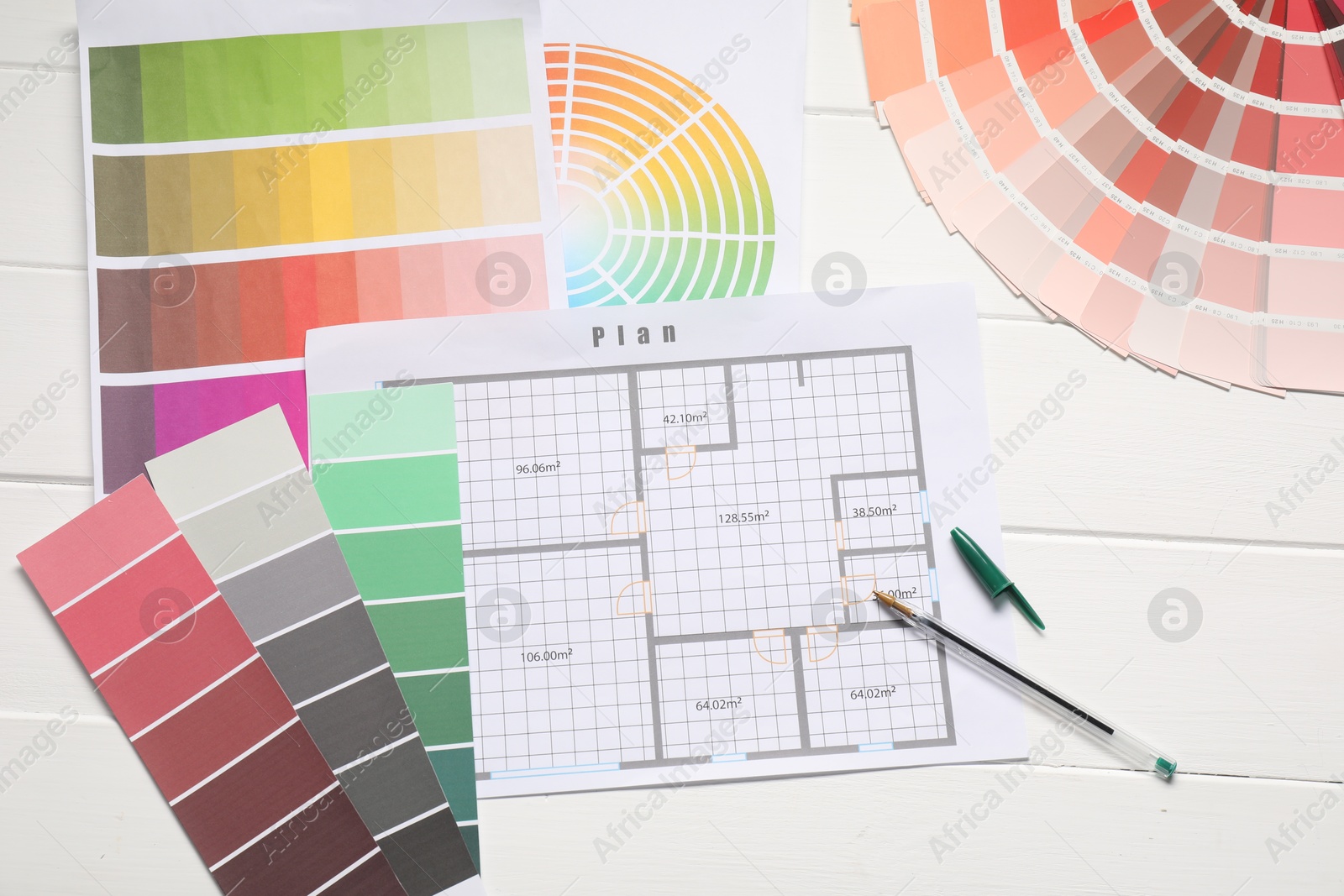 Photo of Designer's workplace with color palettes, floor plan and pen on white wooden table, flat lay