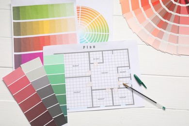 Photo of Designer's workplace with color palettes, floor plan and pen on white wooden table, flat lay