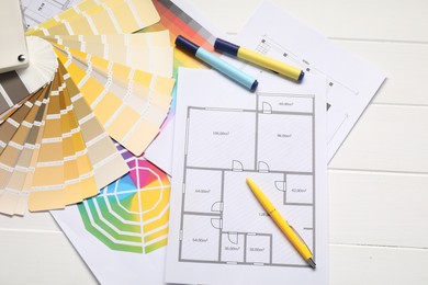 Designer's workplace with color palettes, floor plans and stationery on white wooden table, flat lay