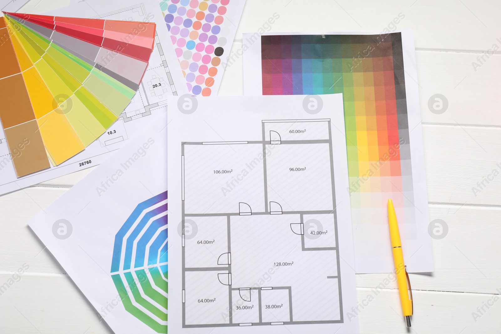 Photo of Designer's workplace with color palettes, floor plans and pen on white wooden table, flat lay