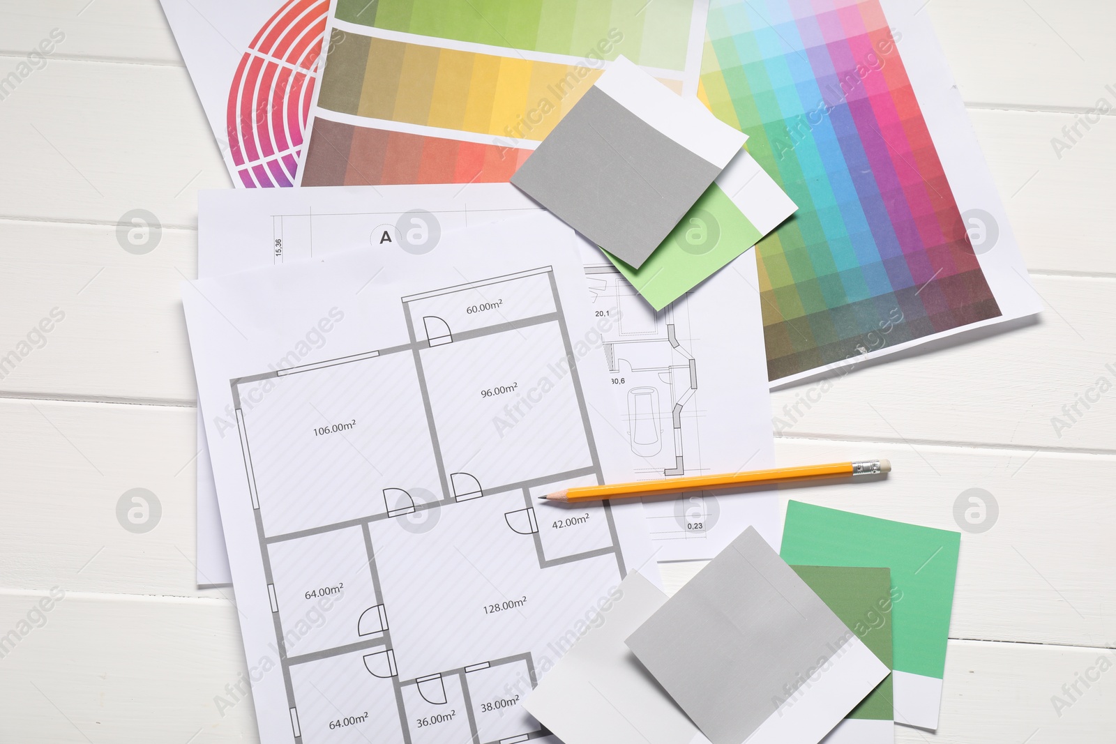 Photo of Designer's workplace with different color palettes, floor plans and pencil on white wooden table, flat lay