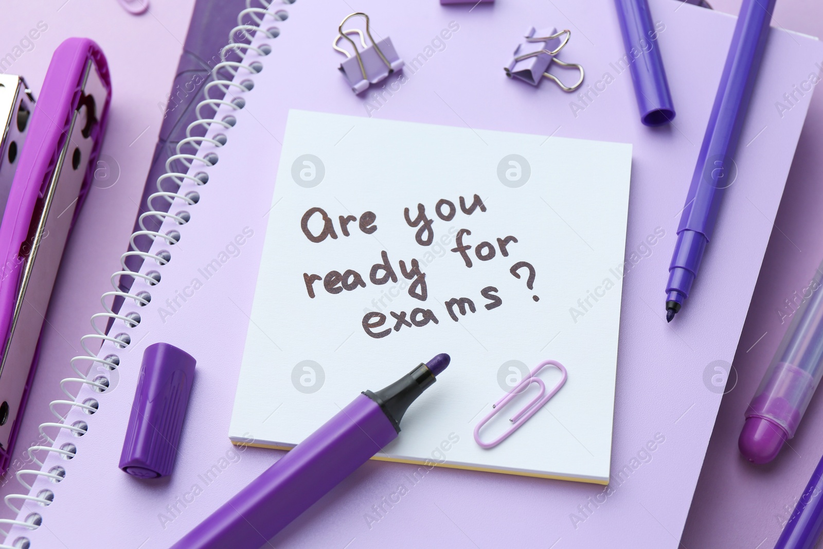 Photo of Paper note with question Are You Ready For Exams and stationery on purple background, above view