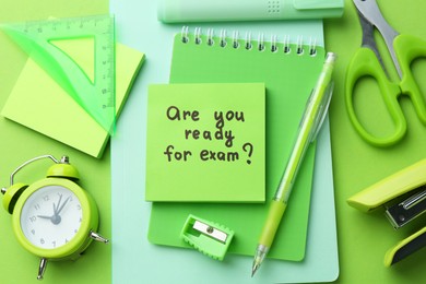 Photo of Paper note with question Are You Ready For Exam and stationery on green background, flat lay