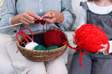 Photo of Grandmother knitting with her granddaughter at home, closeup