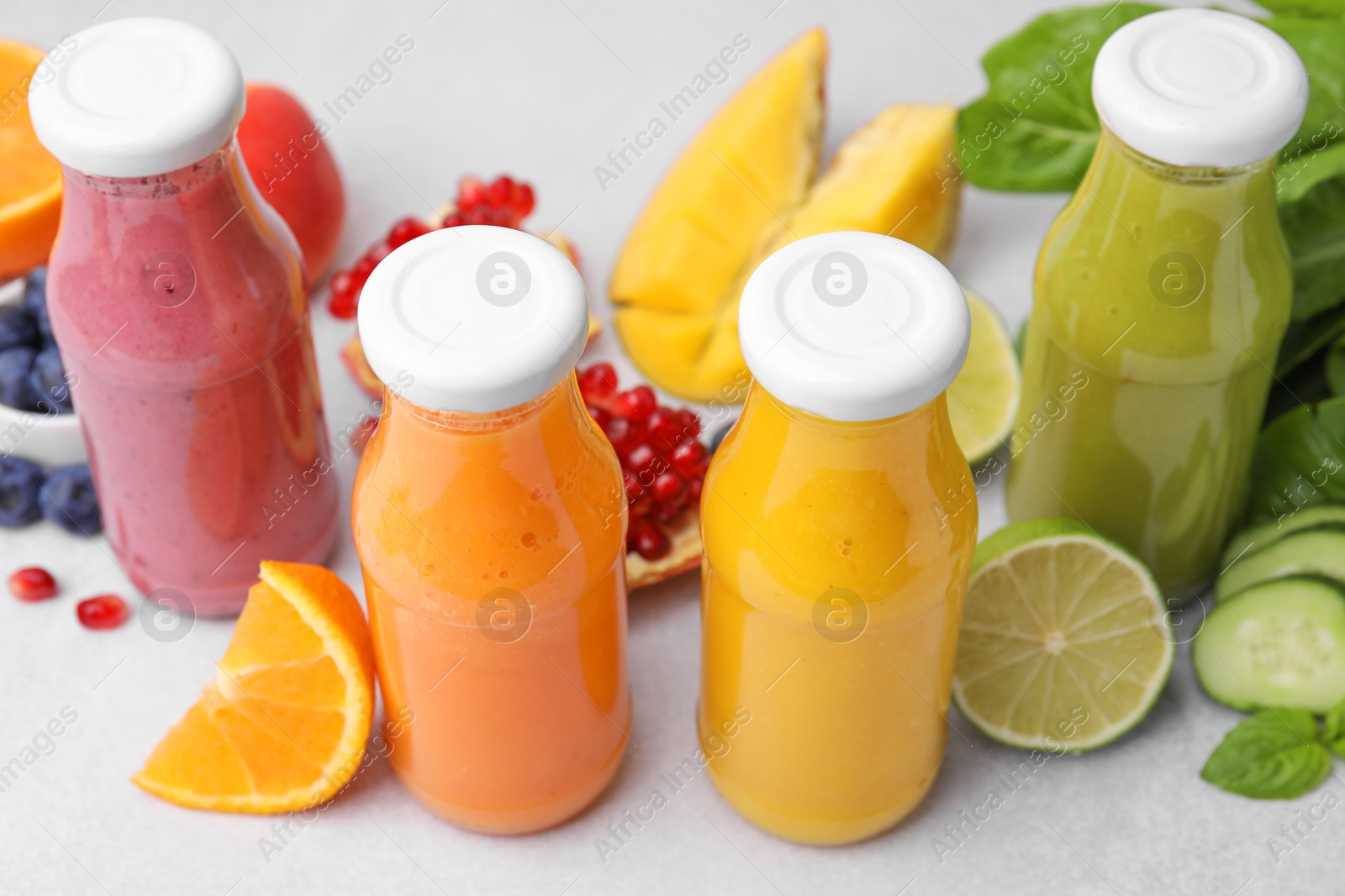 Photo of Glass bottles of tasty smoothies and different products on white table