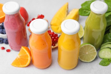 Glass bottles of tasty smoothies and different products on white table