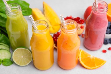 Photo of Glass bottles of tasty smoothies and different products on white table