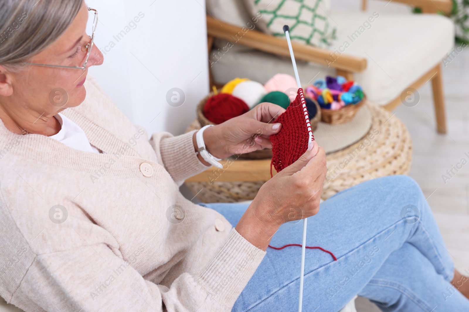 Photo of Senior woman with knitting needles looking at pattern at home